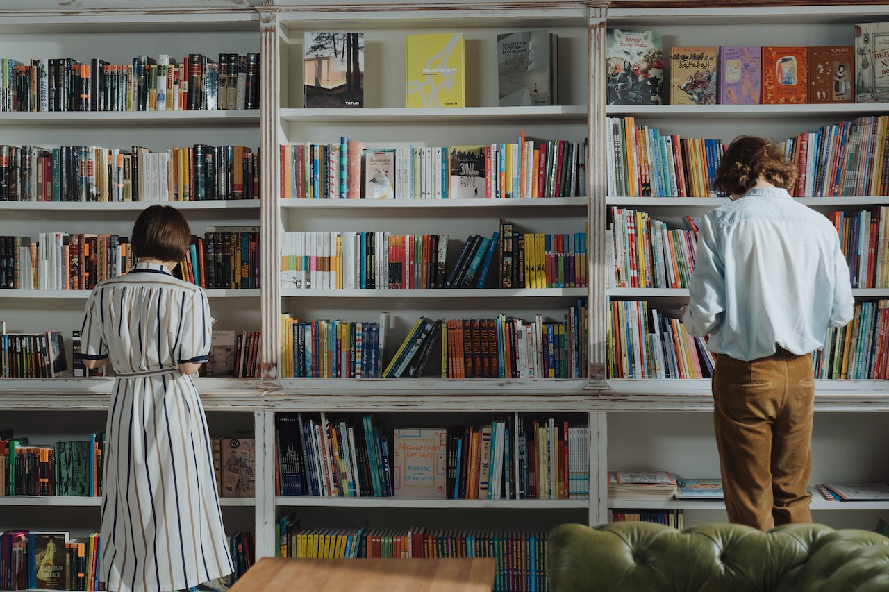 Two young people standing in front of a library shelf